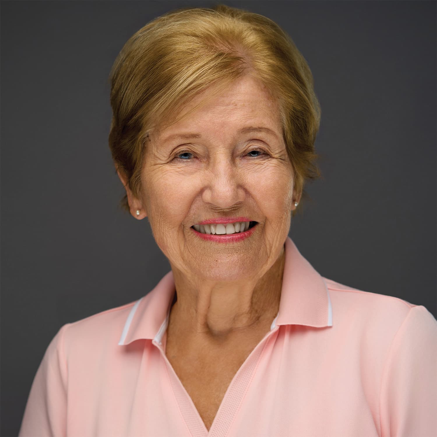 Elsa Bonstein, official author photo: smiling in a pink polo against a studio gray backdrop